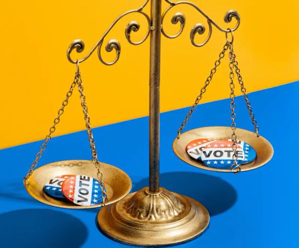 Balance scale with VOTE buttons - Katelyn, Perry - Unsplash