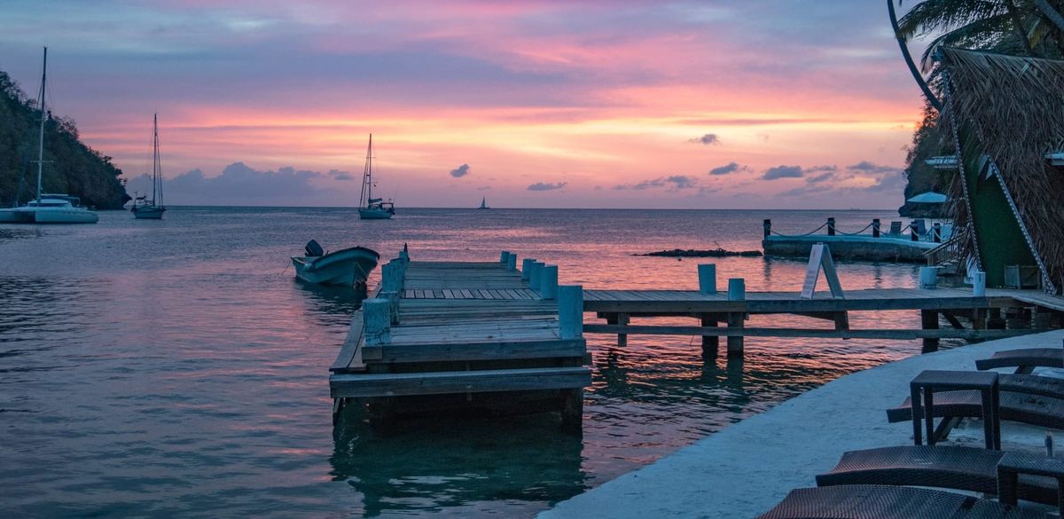 Sunset in a marina in the windward islands, palm trees, sailboats and dock.