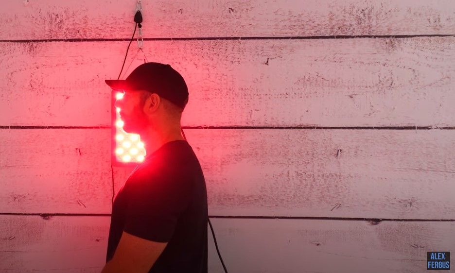 Alex using his HG300 red light panel while it is hanging on his wall