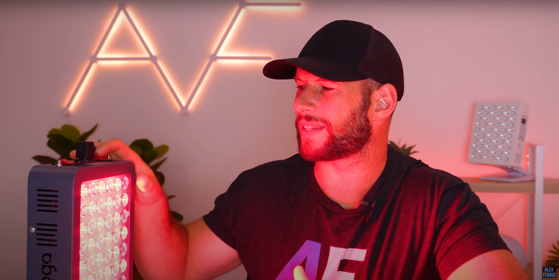 Alex sits beside the HG300 tabletop red light therapy panel bathed in therapeutic red light