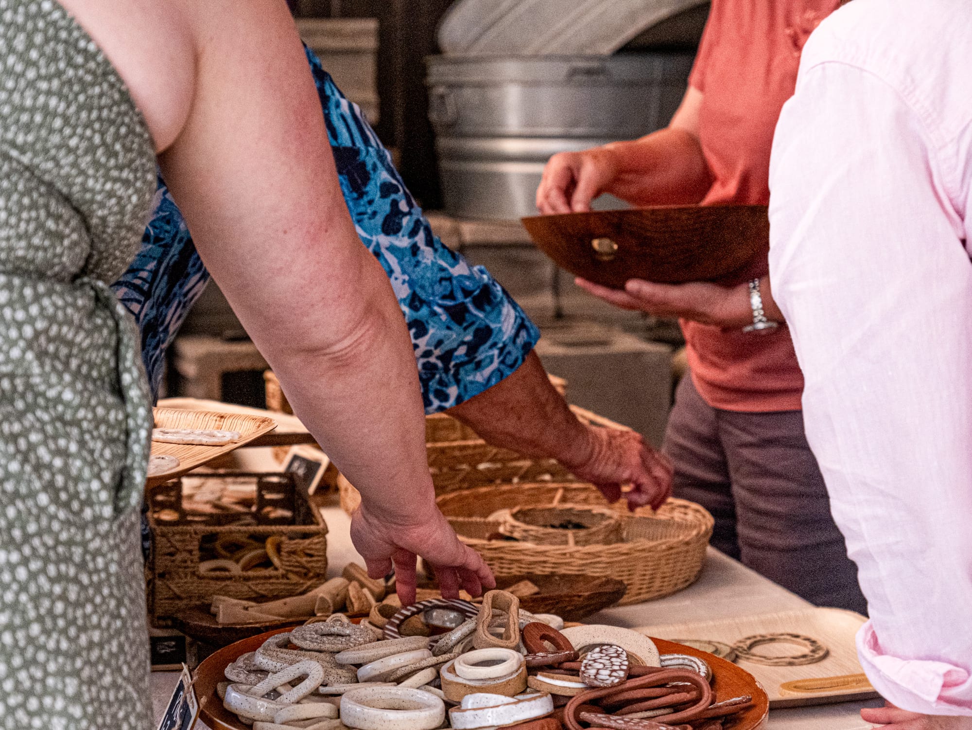 A group of people extend their arms into baskets of colorful beads and cut-out shapes.