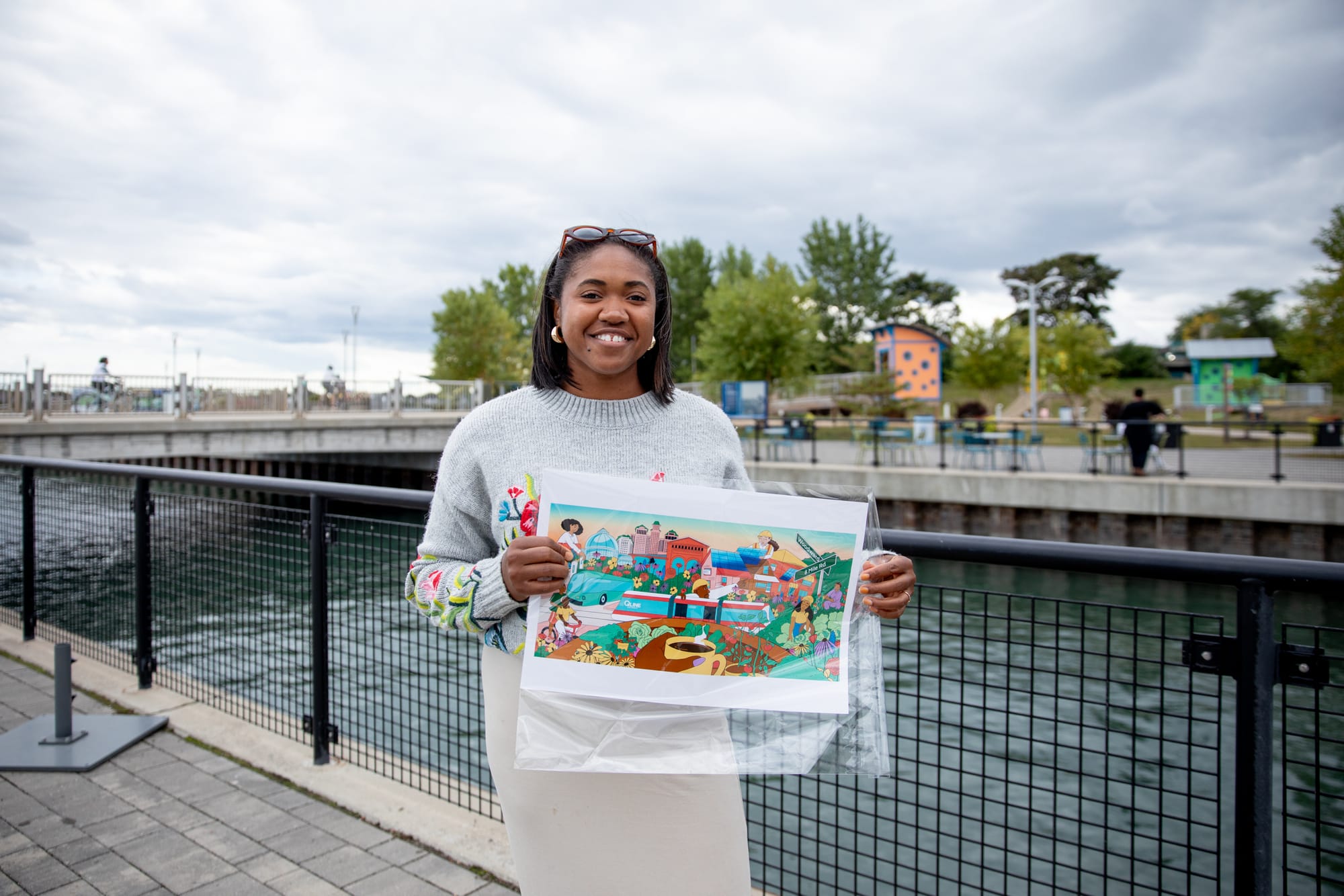 A woman stands outdoors holding up a picture featuring animated artwork.