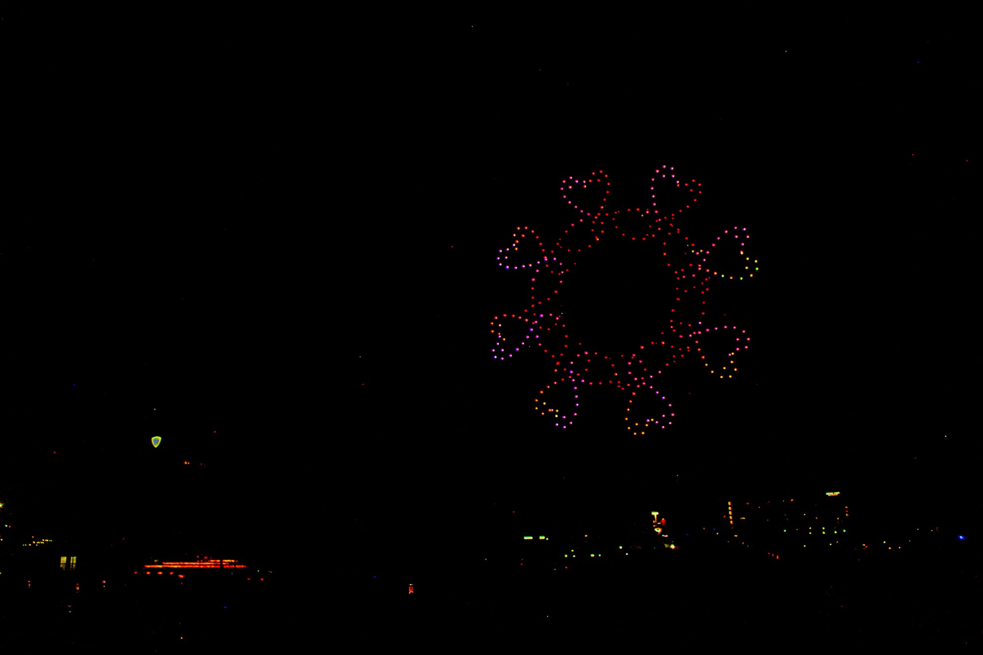Hundreds of drones create a circle of red and yellow facing each other to make the shape of hearts.