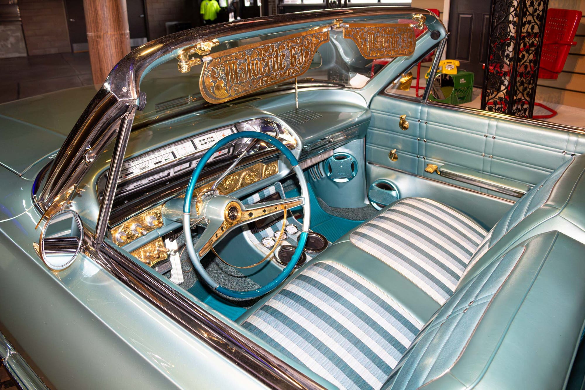 The interior of a classic lowrider with blue paint, blue and white seats, and gold accents.