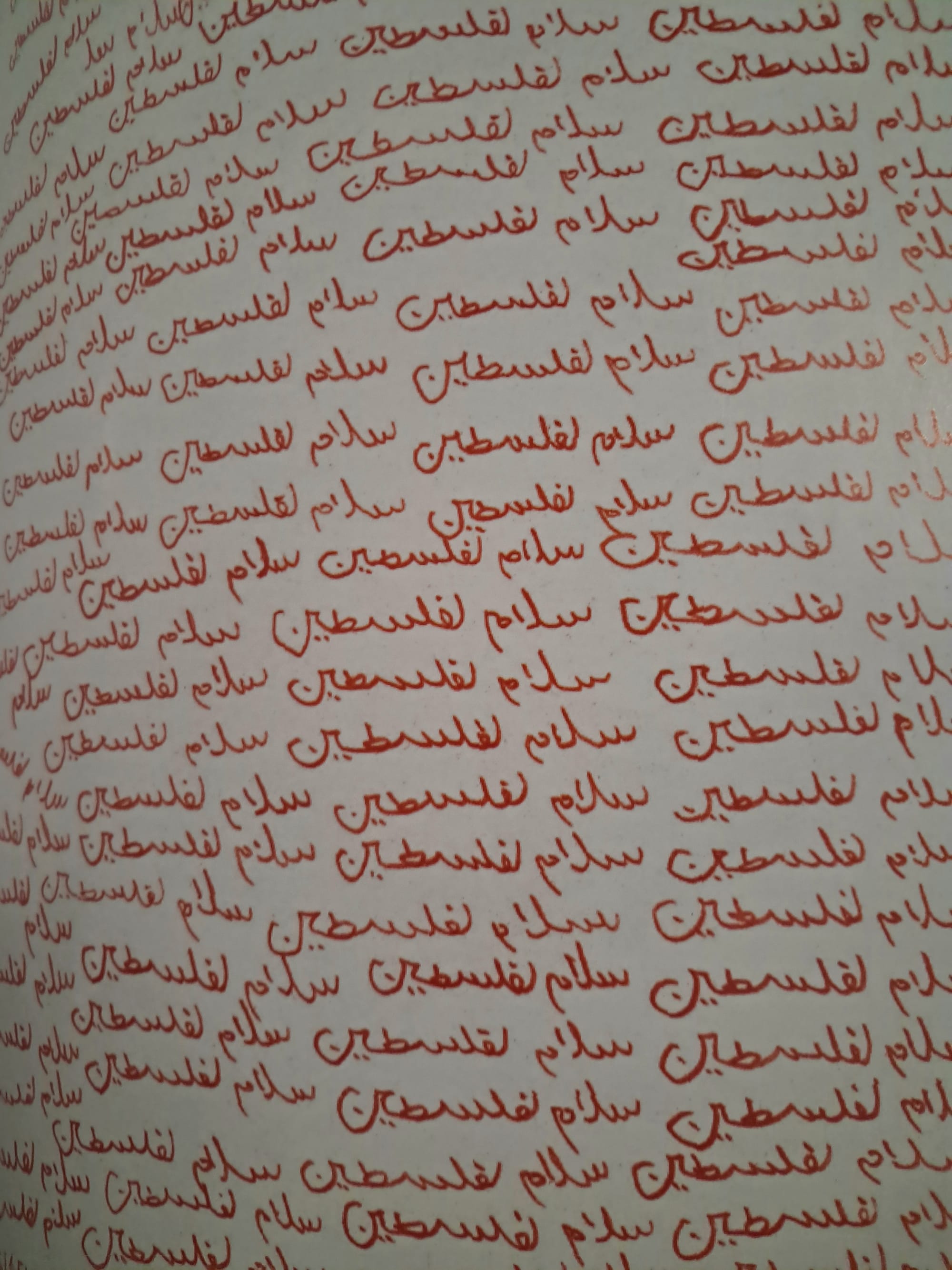 Several repetitions of the phrase 'Peace in Palestine' in Arabic, written by hand in red on a white background, then printed in a book.