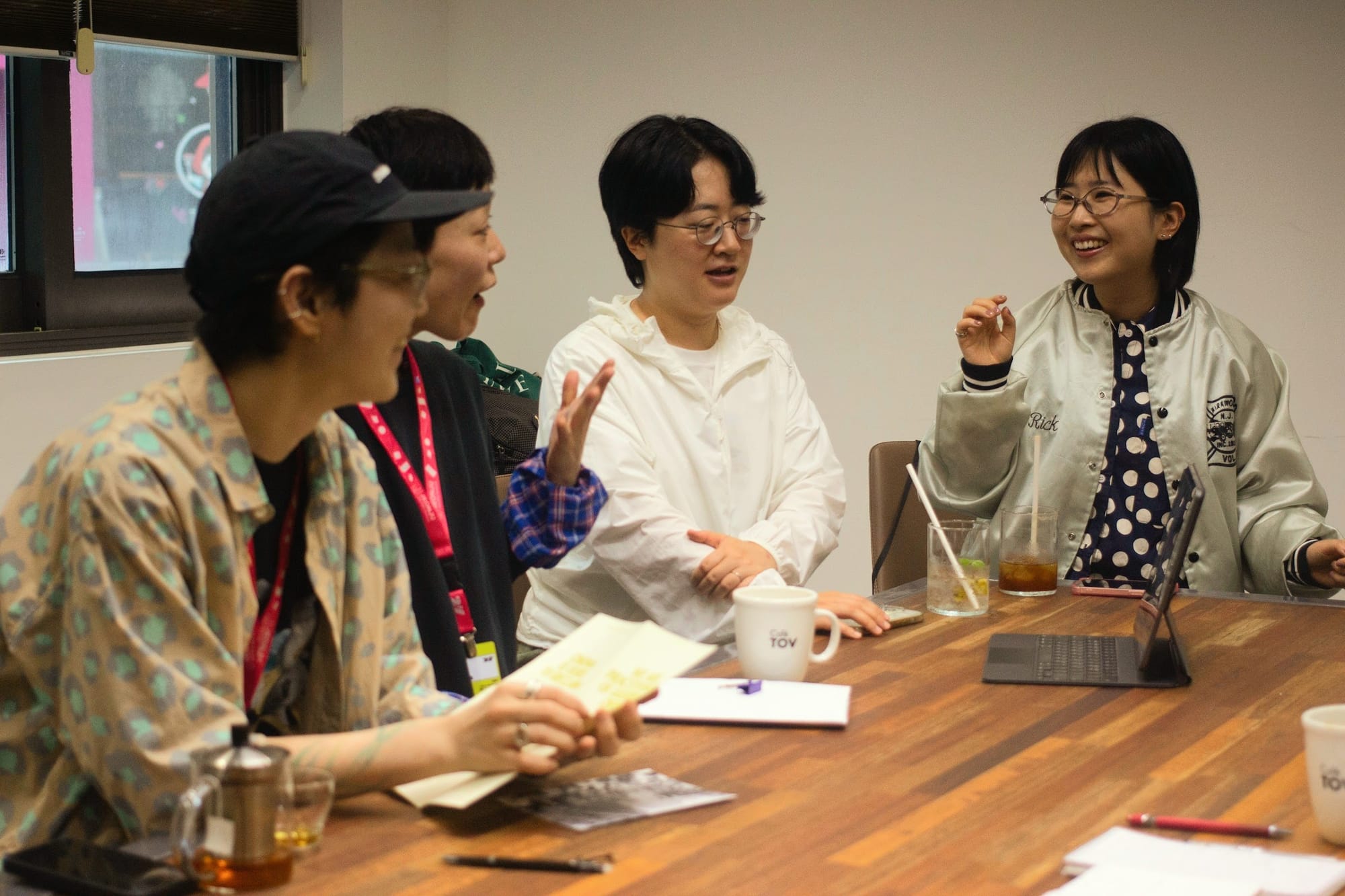 Four women sit around a table, discussing energetically, gesturing with their hands.