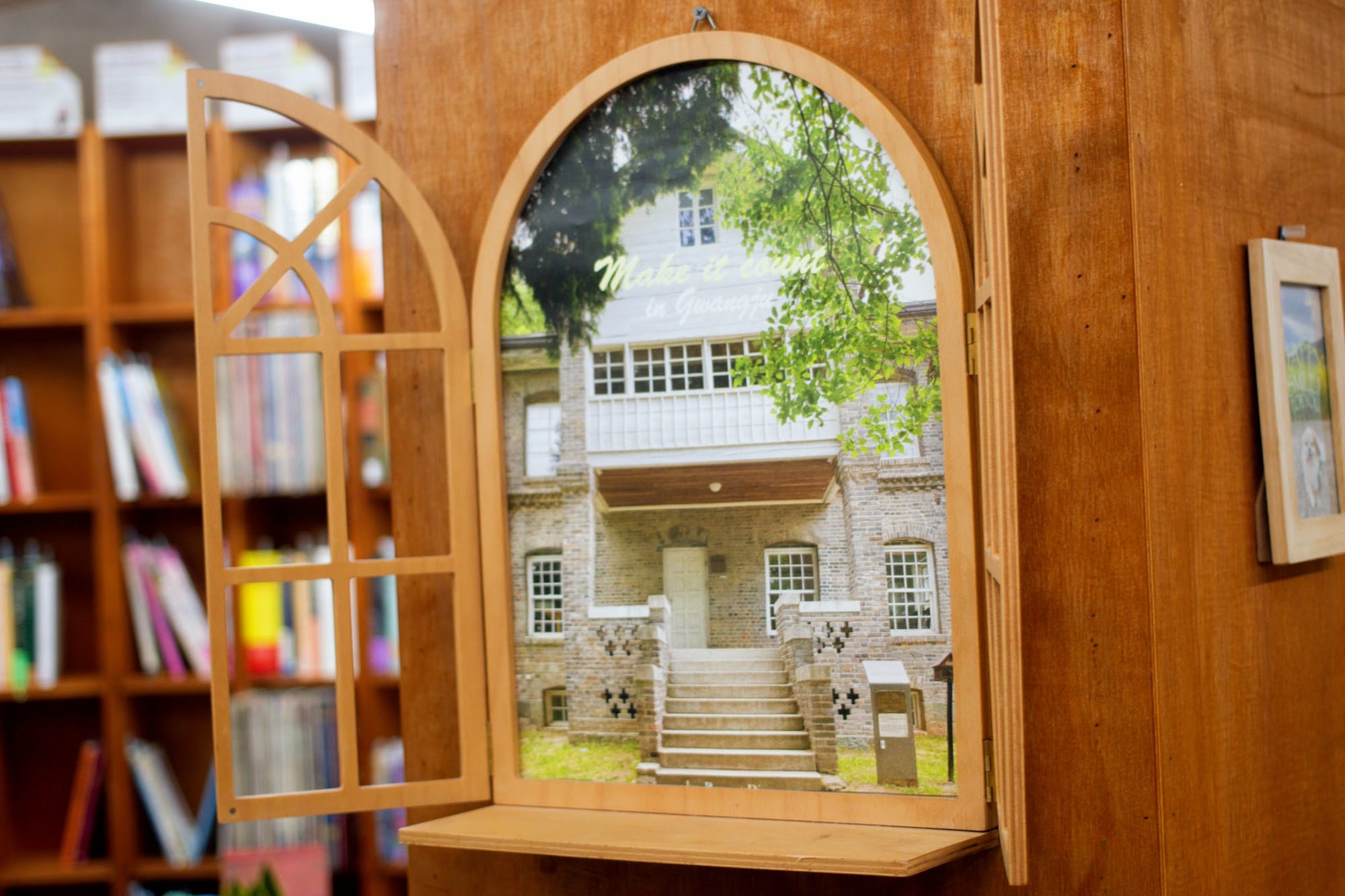 A photo displayed inside a bookstore, with a wooden frame in the shape of an arched window, with a cover that opens.