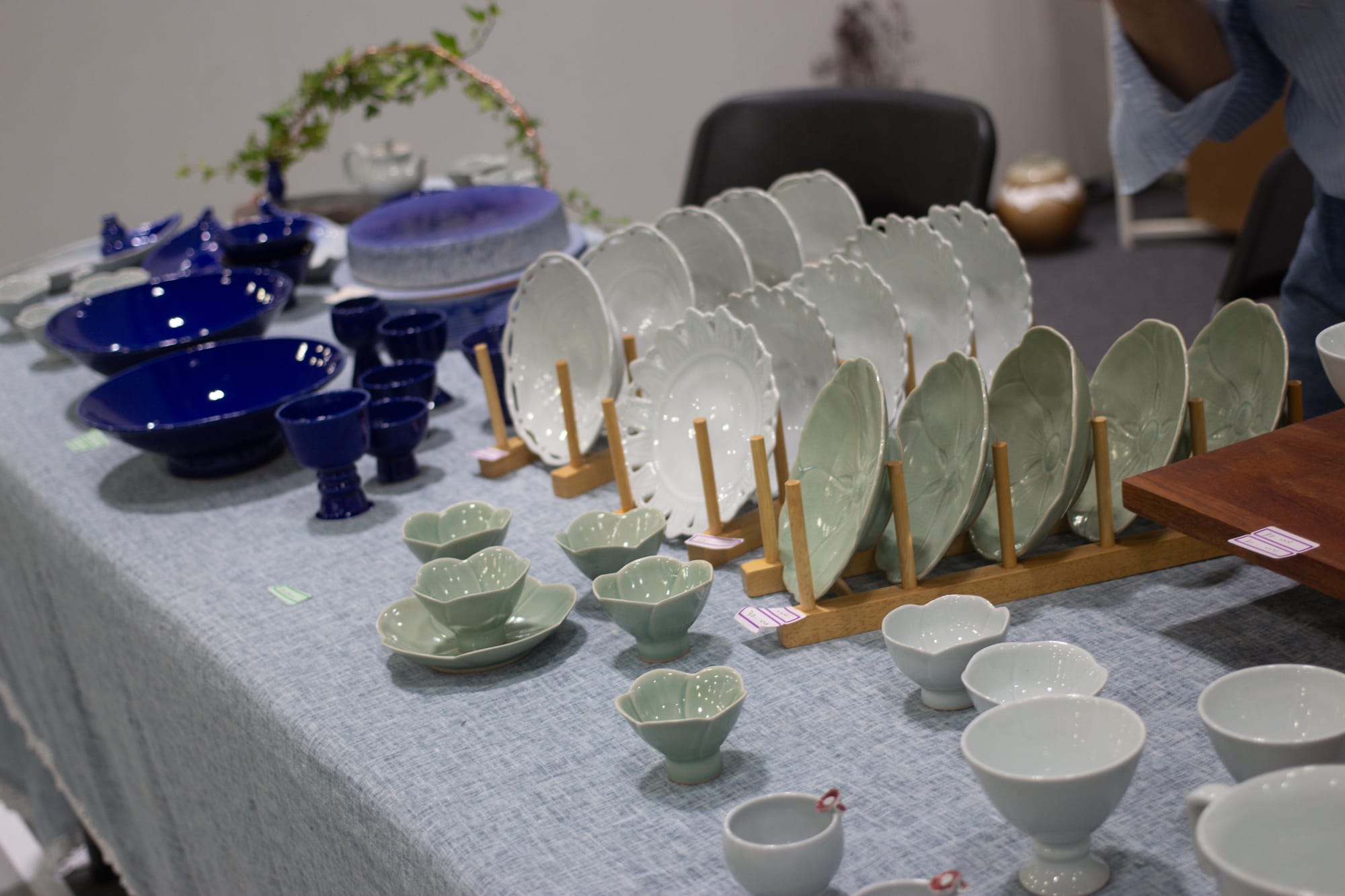 Display of dark blue, white, and light green ceramic bowls and plates. Some are shaped like flowers.