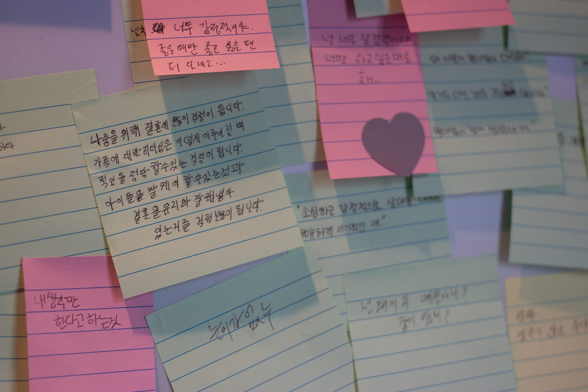 A collection of several post-it notes layered over each other, all with messages written in black pen in Korean.