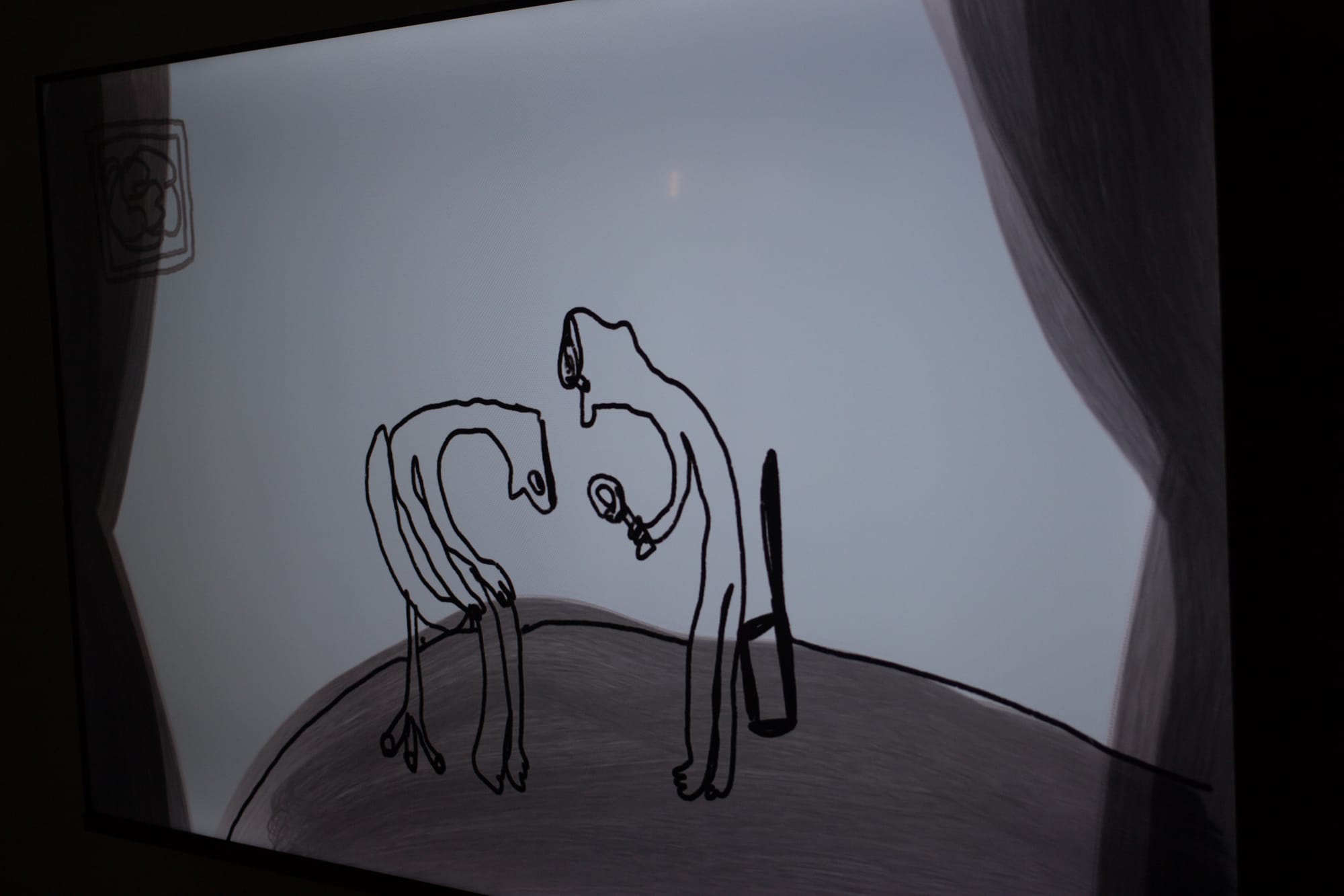 A still from an animation with scribbly lines. A motif of curtains decorates the sides of the screen. One character sits in a chair, bending his neck. The other prepares to examine the exposed head with a magnifying glass.