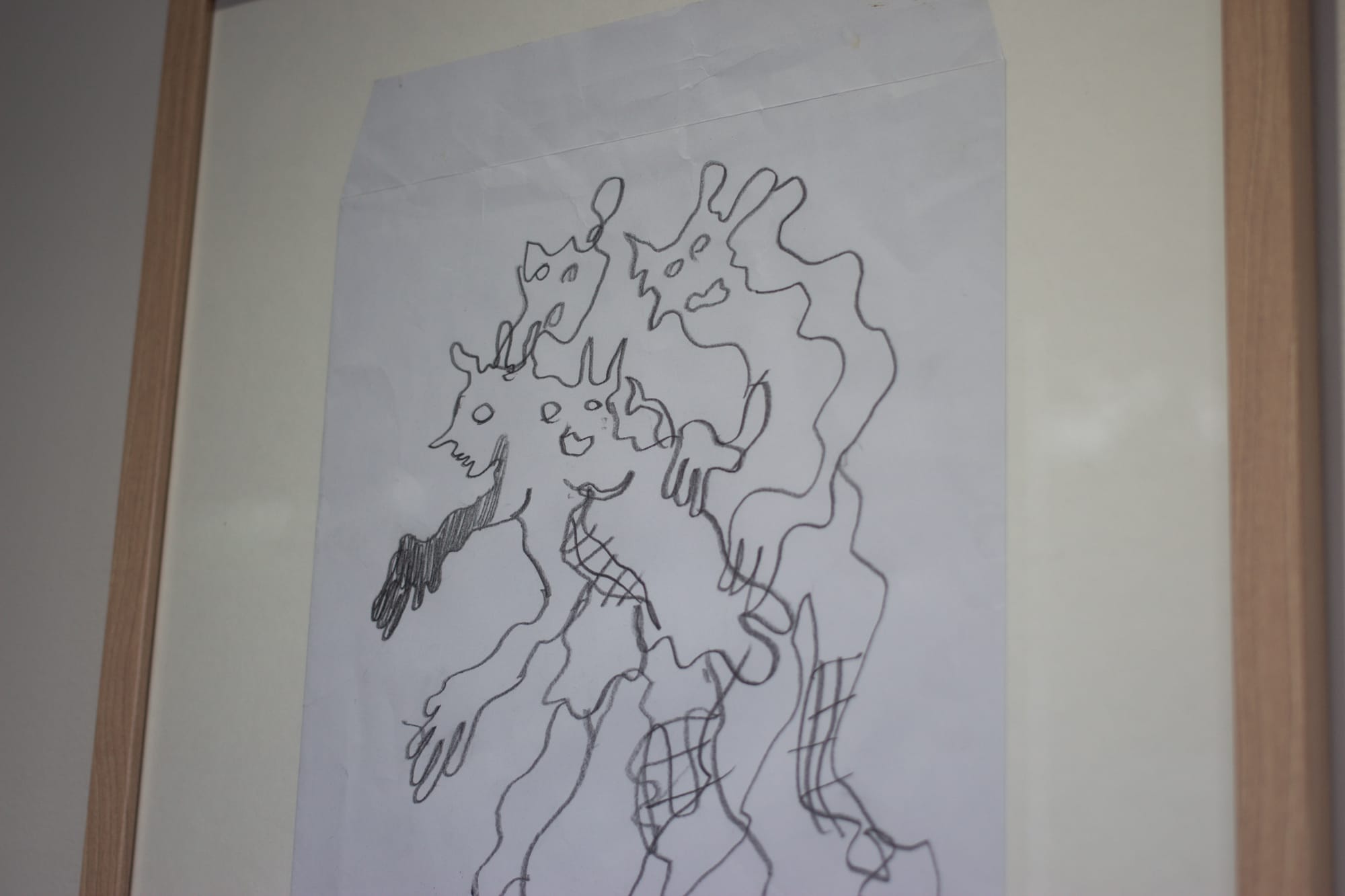 A drawing on a large white envelope. One monster with many faces, hands, and legs or many monsters fused together.