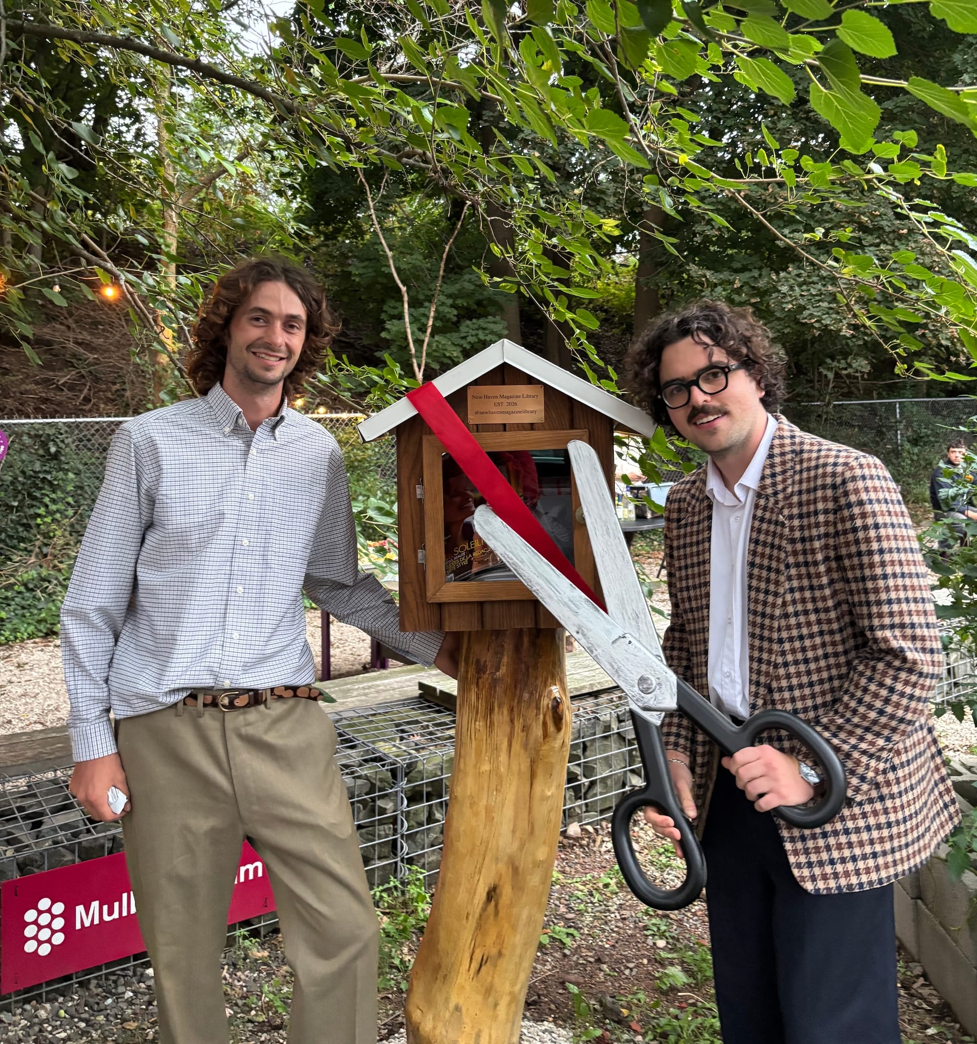 A photo of Oliver Egger and Peter Fulweiler with a huge pair of scissors, standing in front of the library.