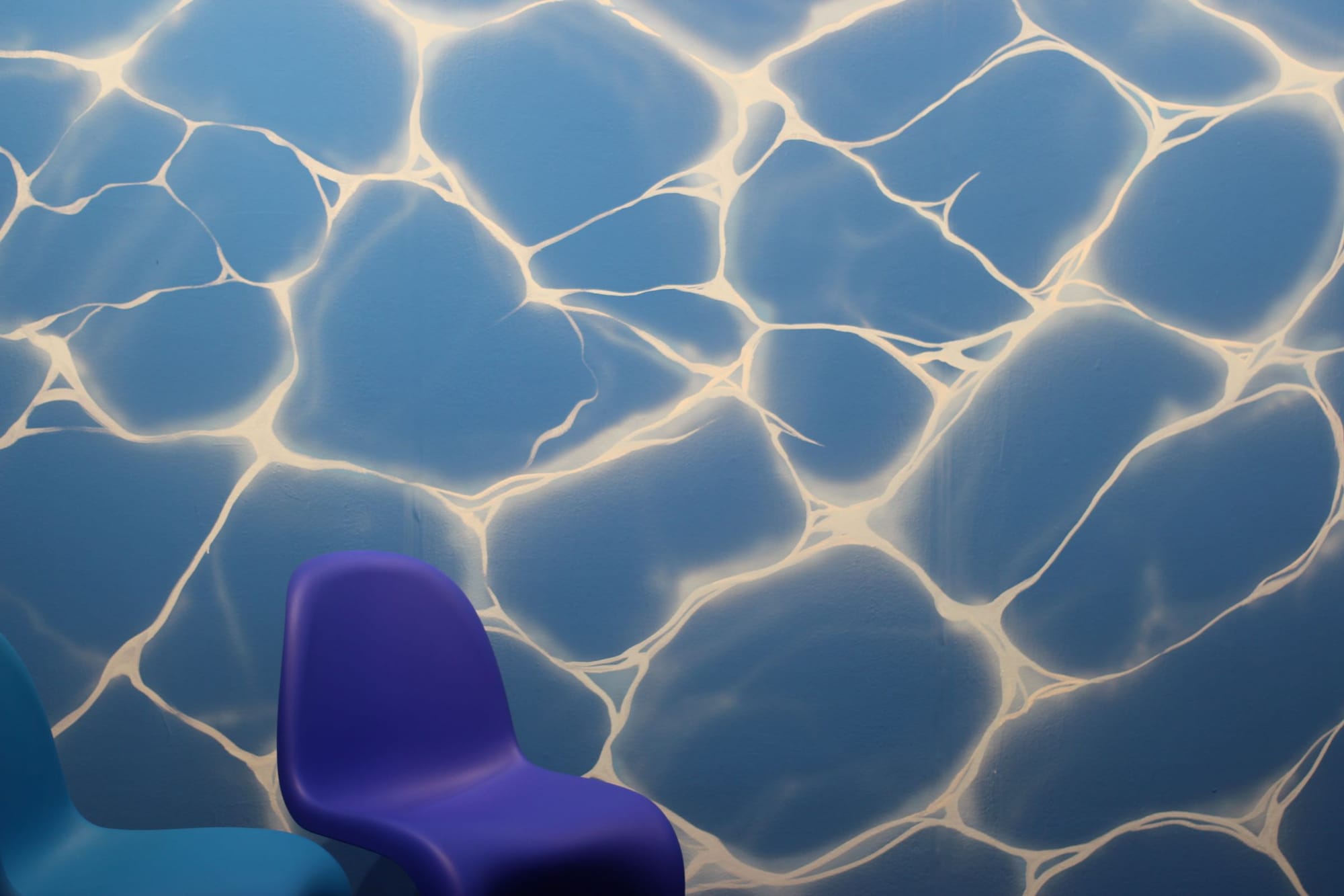 Large expanse of blue with webs of white light. Two plastic chairs are in front.