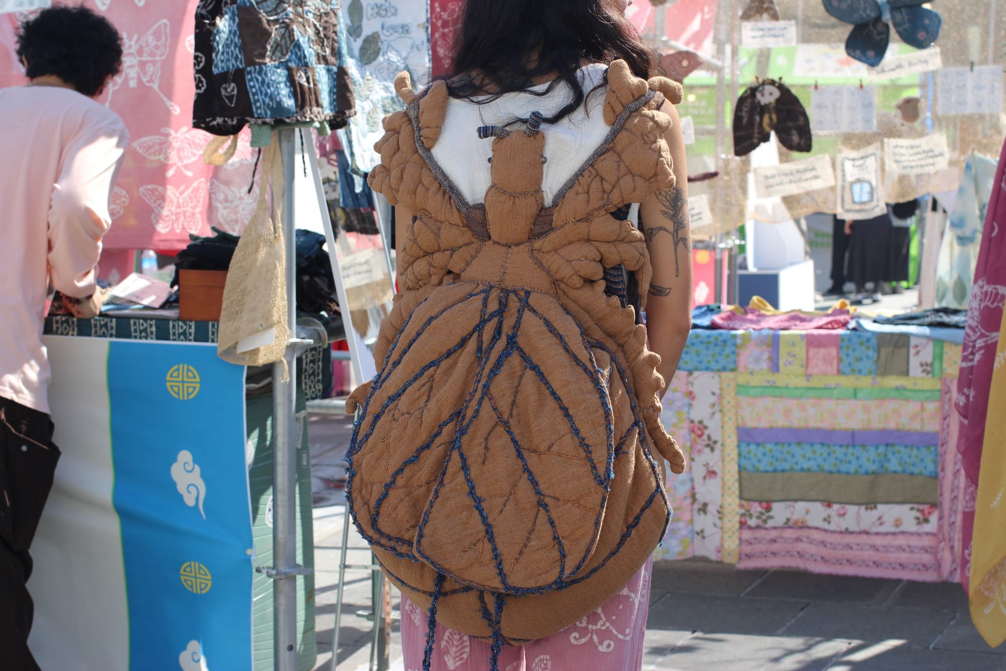 Seansopha wearing a huge brown backpack in the shape of a moth.