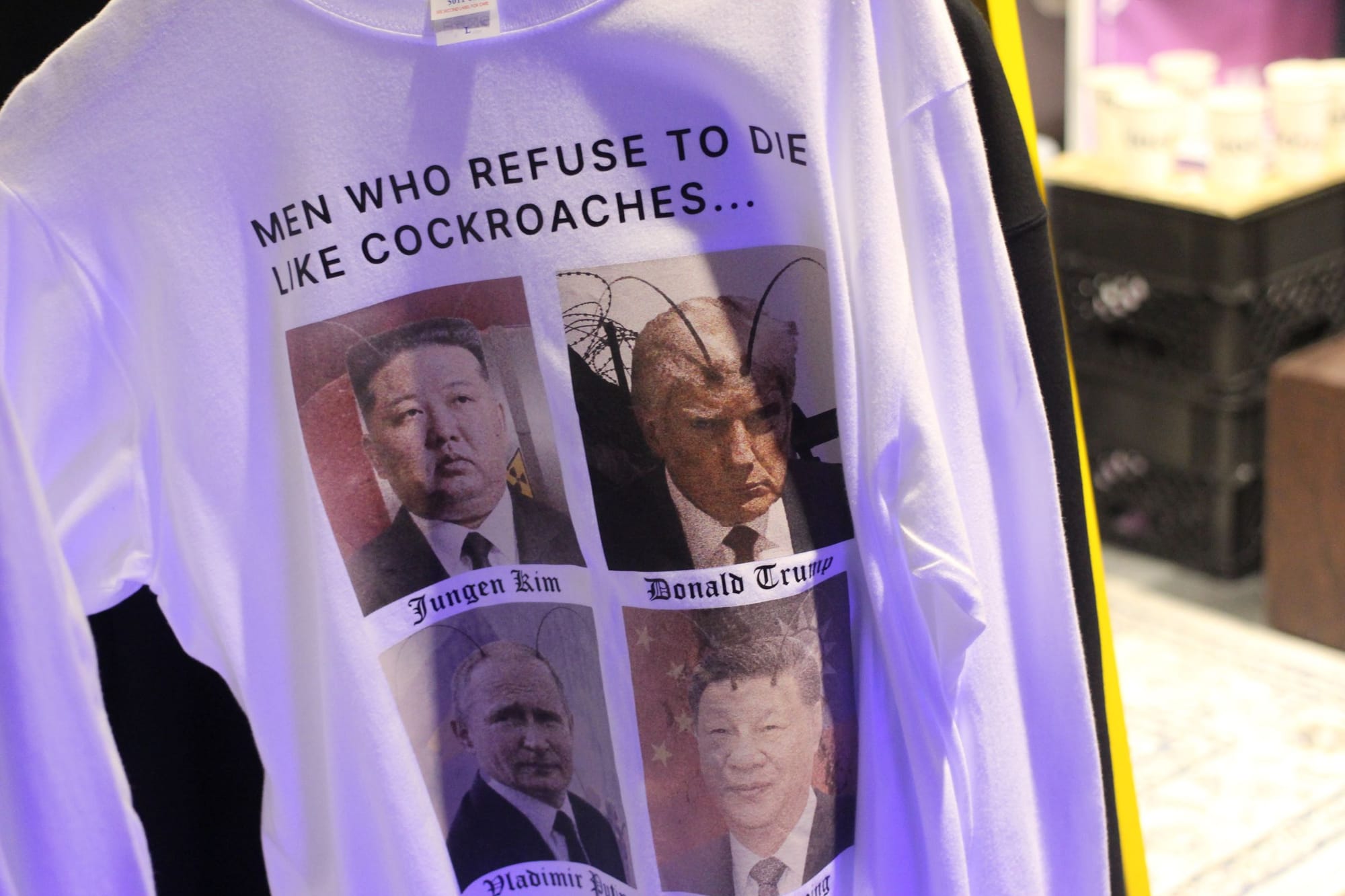 White tee shirt with the text "MEN WHO REFUSE TO DIE LIKE COCKROACHES..." and pictures of Kim Jong Un, Donald Trump, Vladimir Putin, and Xi Jinping, edited to look like cockroaches.