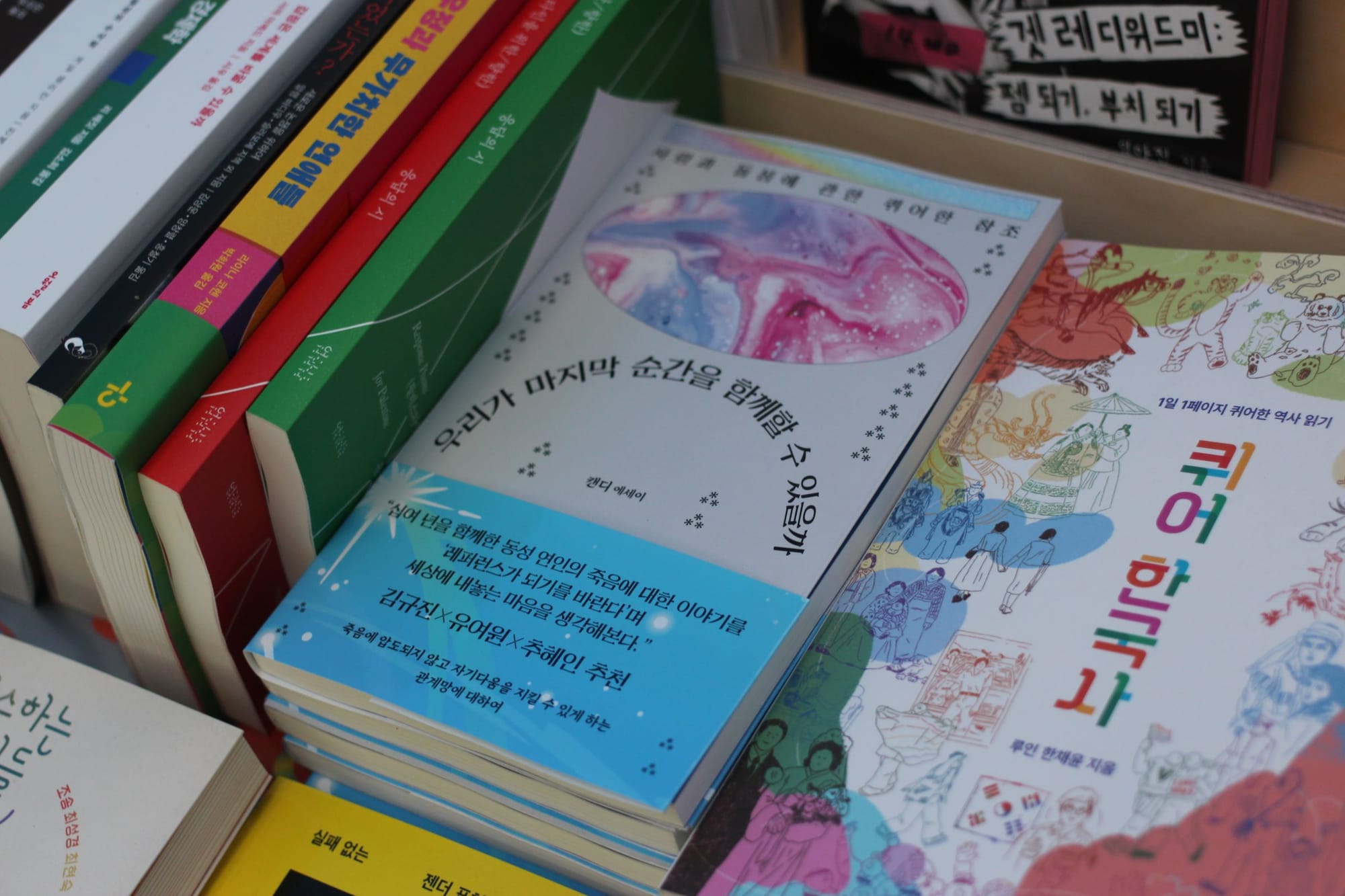 A book with iridescent-looking blue and purple sections on a gray background, among many other books on display.