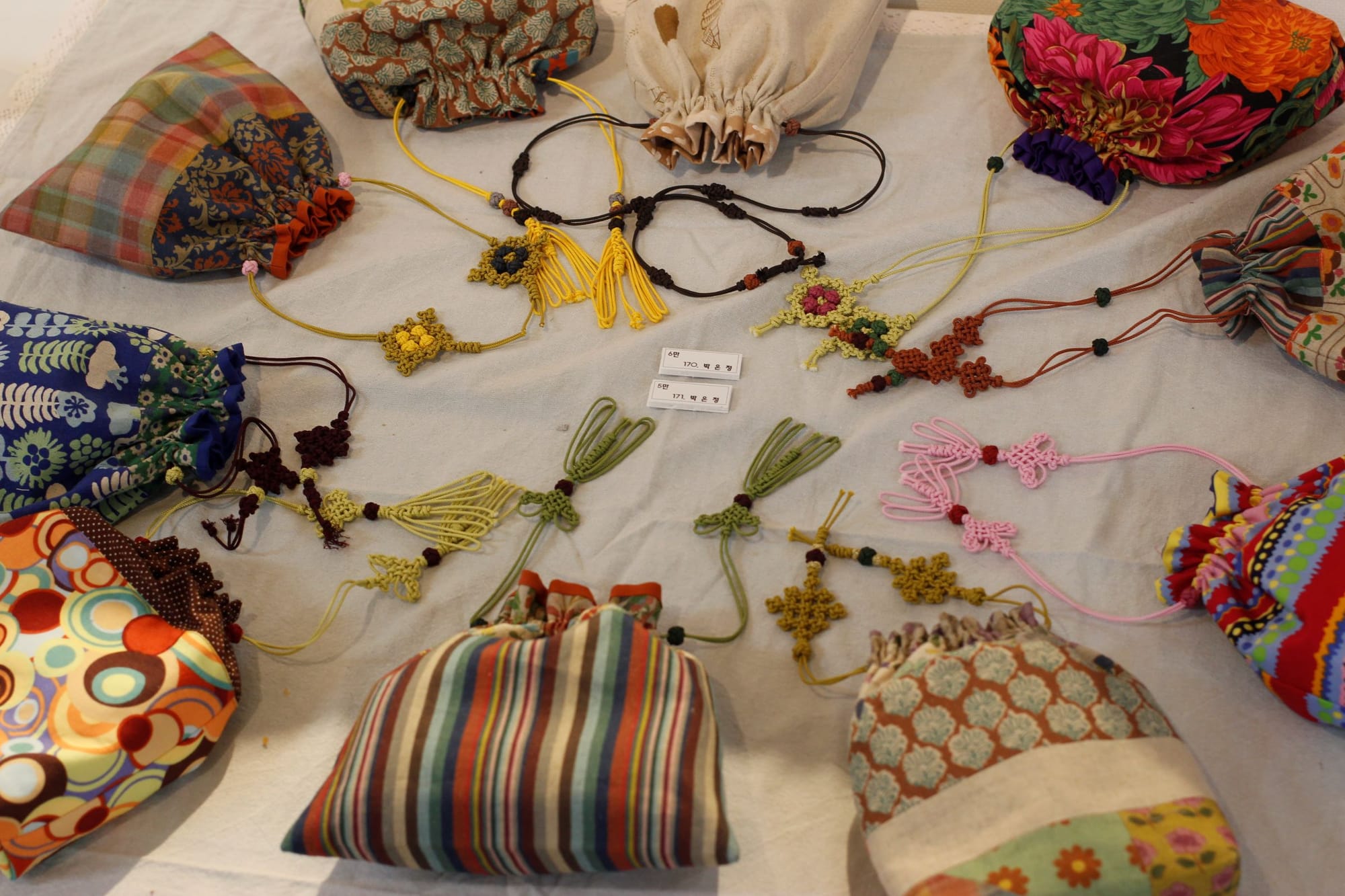 Ten pouches in a variety of fabric patterns in a circle with traditional Korean knot closures draped toward the center.