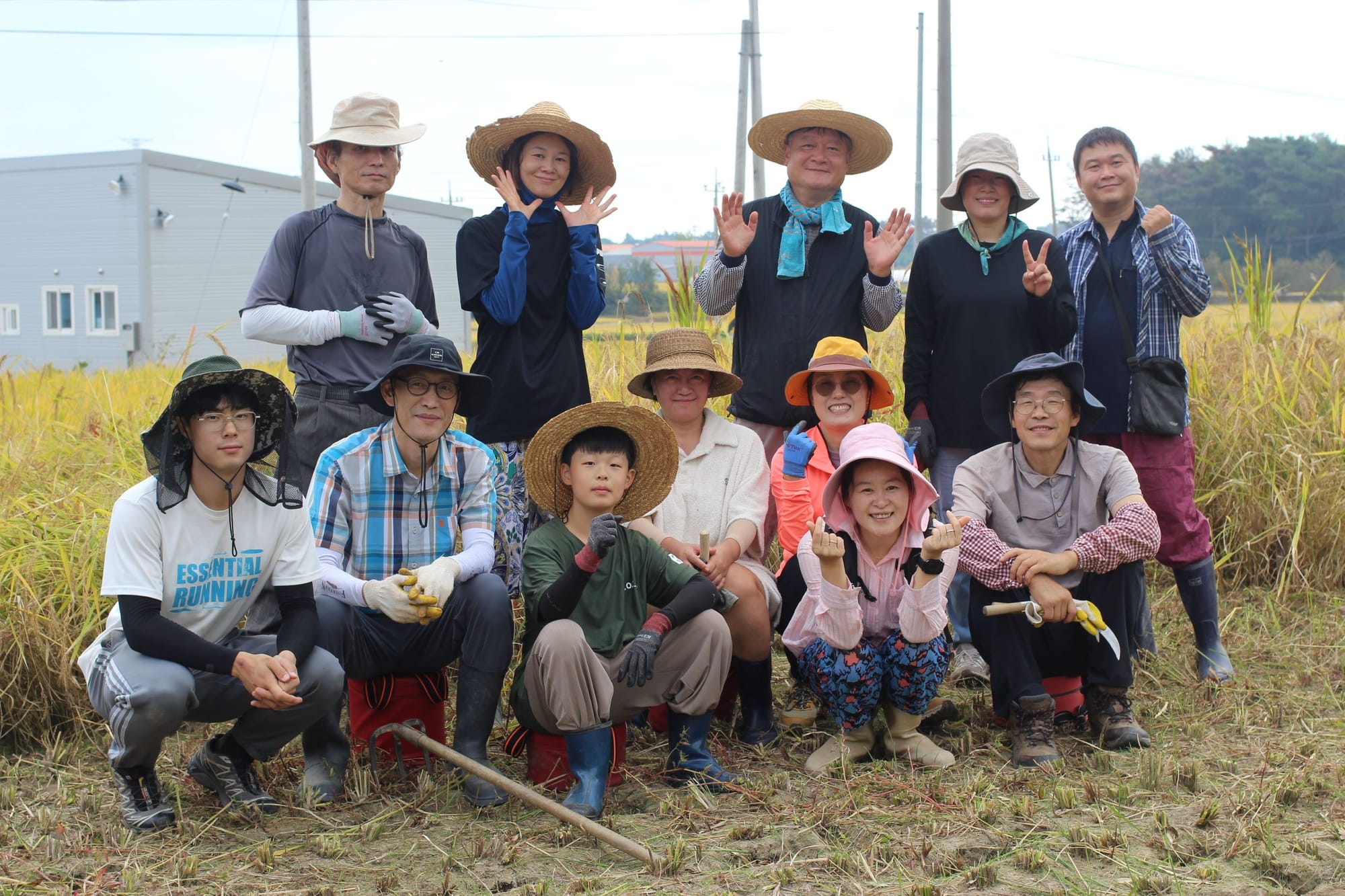 Several people in farming attire pose for a group photo in a rice field.