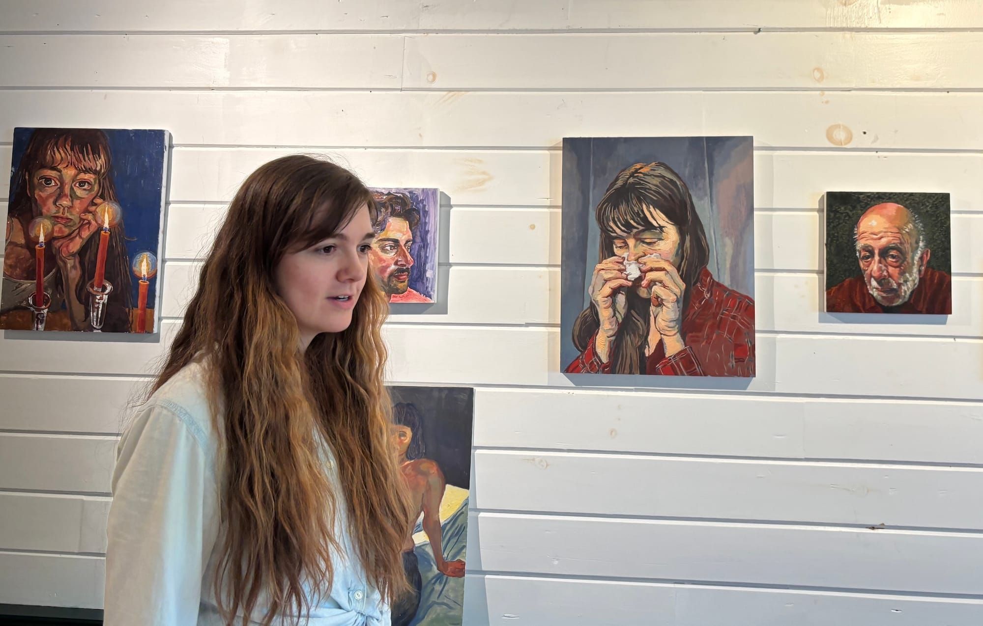 Artist August Lamm stands in front of her portraits.