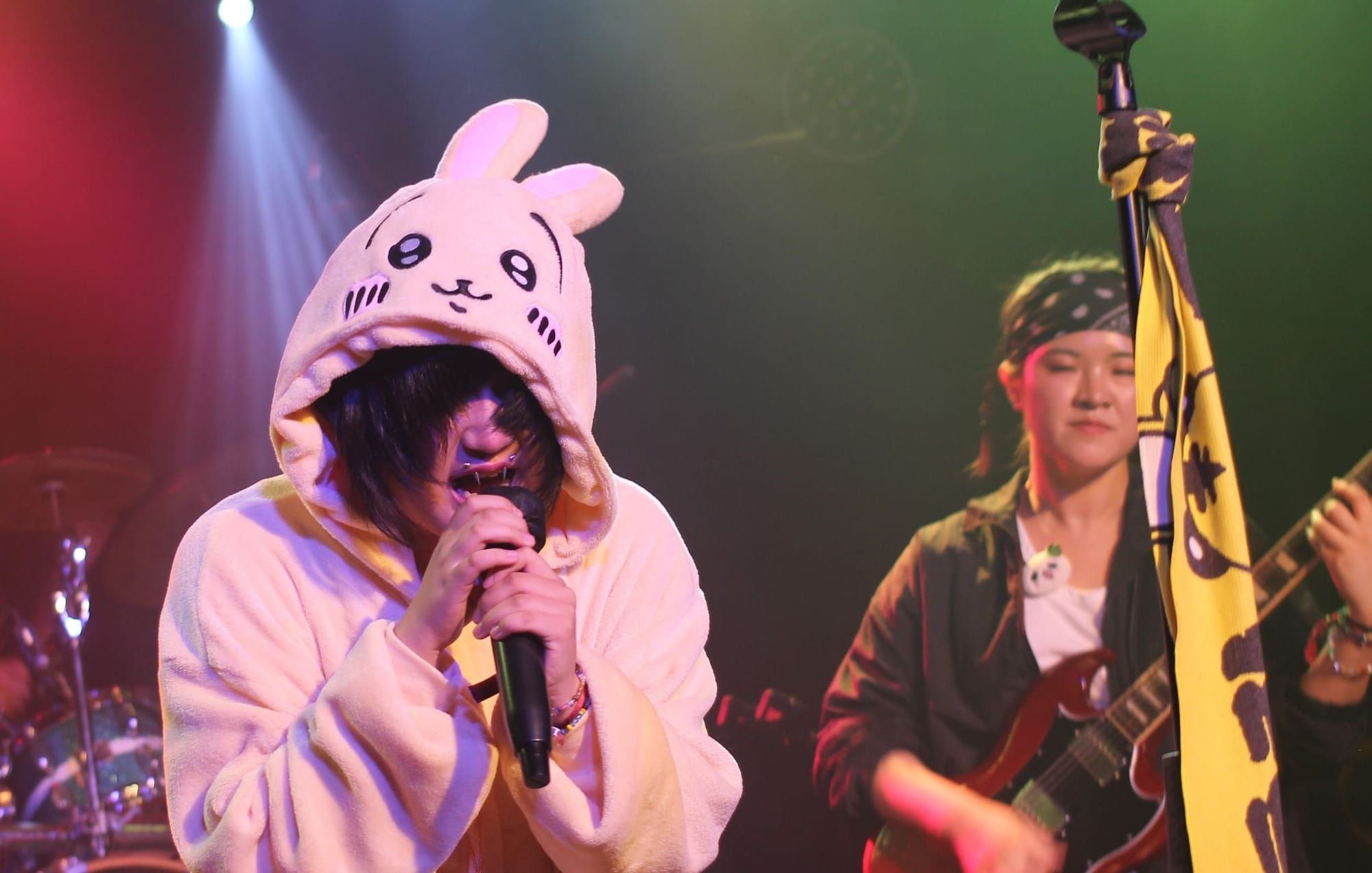 Singer Asuka, with spiky metallic lip piercings and a bunny character onesie, screams into the mic.