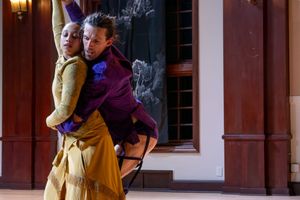 Two people hold each other; one is wearing a gold dress and the other is wearing a purple shirt.