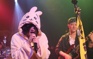 Singer Asuka, with spiky metallic lip piercings and a bunny character onesie, screams into the mic.