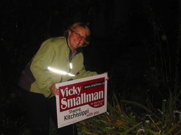 Vicky gleefully installing an election sign on a lawn.