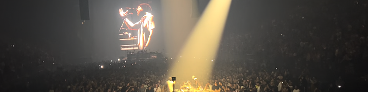 a photo of KTM performing, surrounded by a sea of people, with a projection of him up on a giant screen