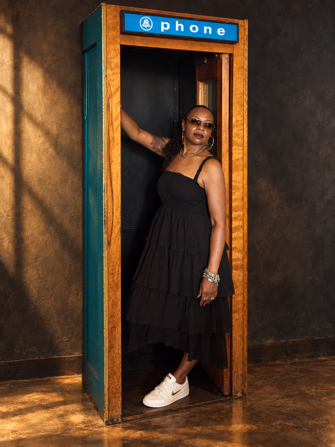 Precious “Preciosa” Myers-Brown standing in a vintage wooden and teal phone booth.