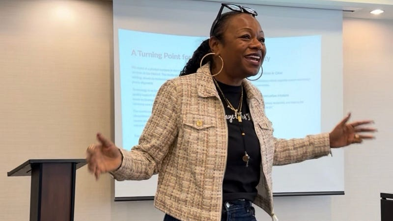 Precious “Preciosa” Myers-Brown speaking at a Washington, DC tech equity event, gesturing with both hands open in front of a slide titled “A Turning Point for DC’s Disability Services.”