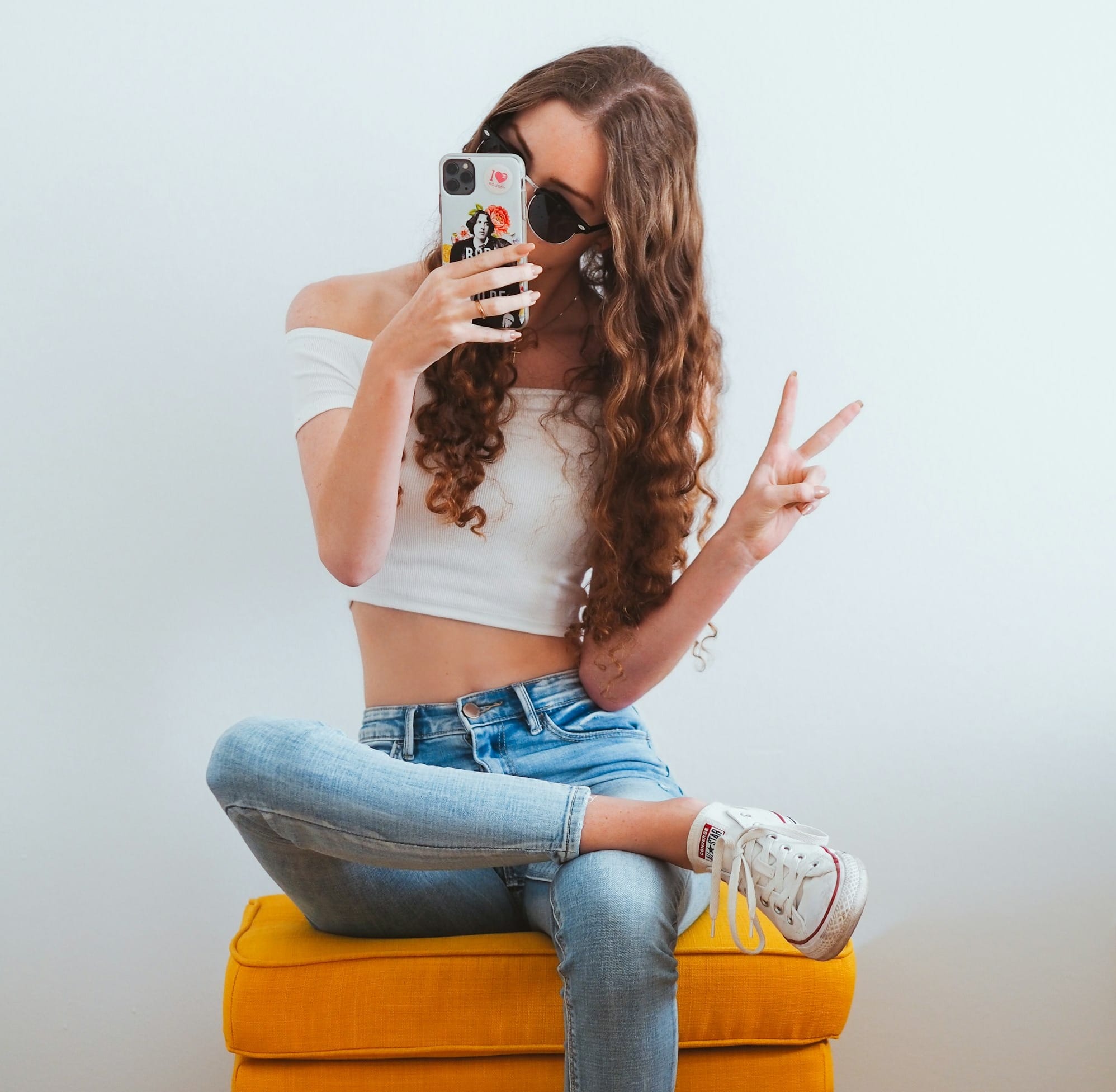 woman in pink tank top and blue denim jeans sitting on yellow chair