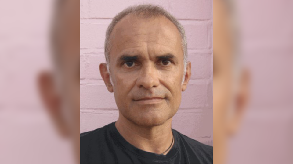 A portrait of Adrian Hart is shown against a backdrop of a pastel-pink brickwall.