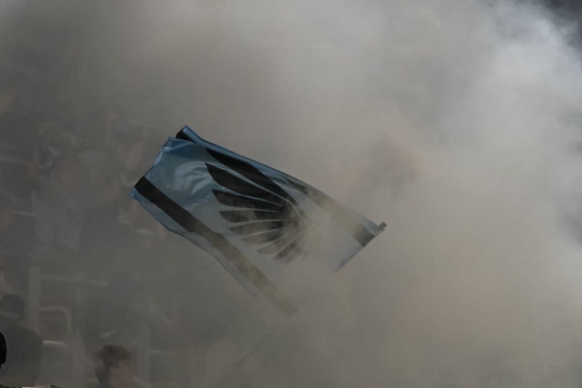 An artistic photo of a MNUFC flag surrounded by smoke. Image credit: Dan Mick
