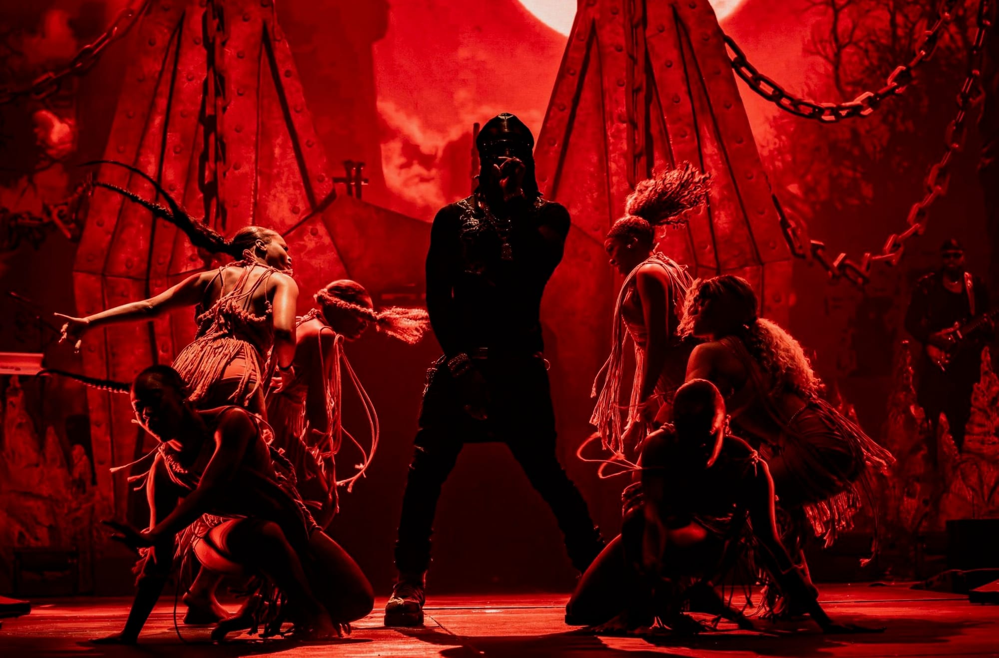 Rema at the O2 with a red hue covering the image and backup dancers around him