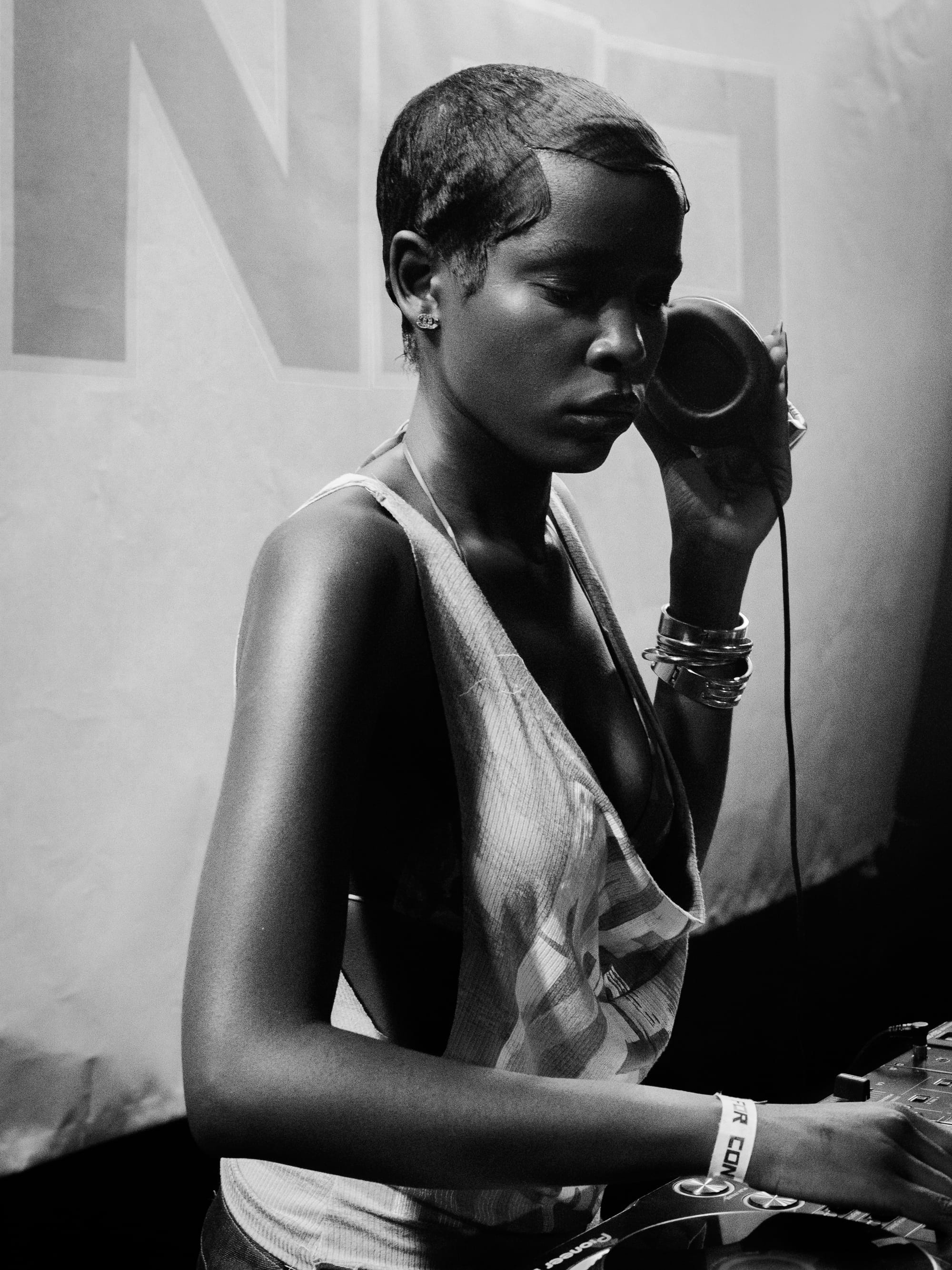 Black-and-white portrait of a DJ wearing headphones, concentrating while mixing music at a turntable.