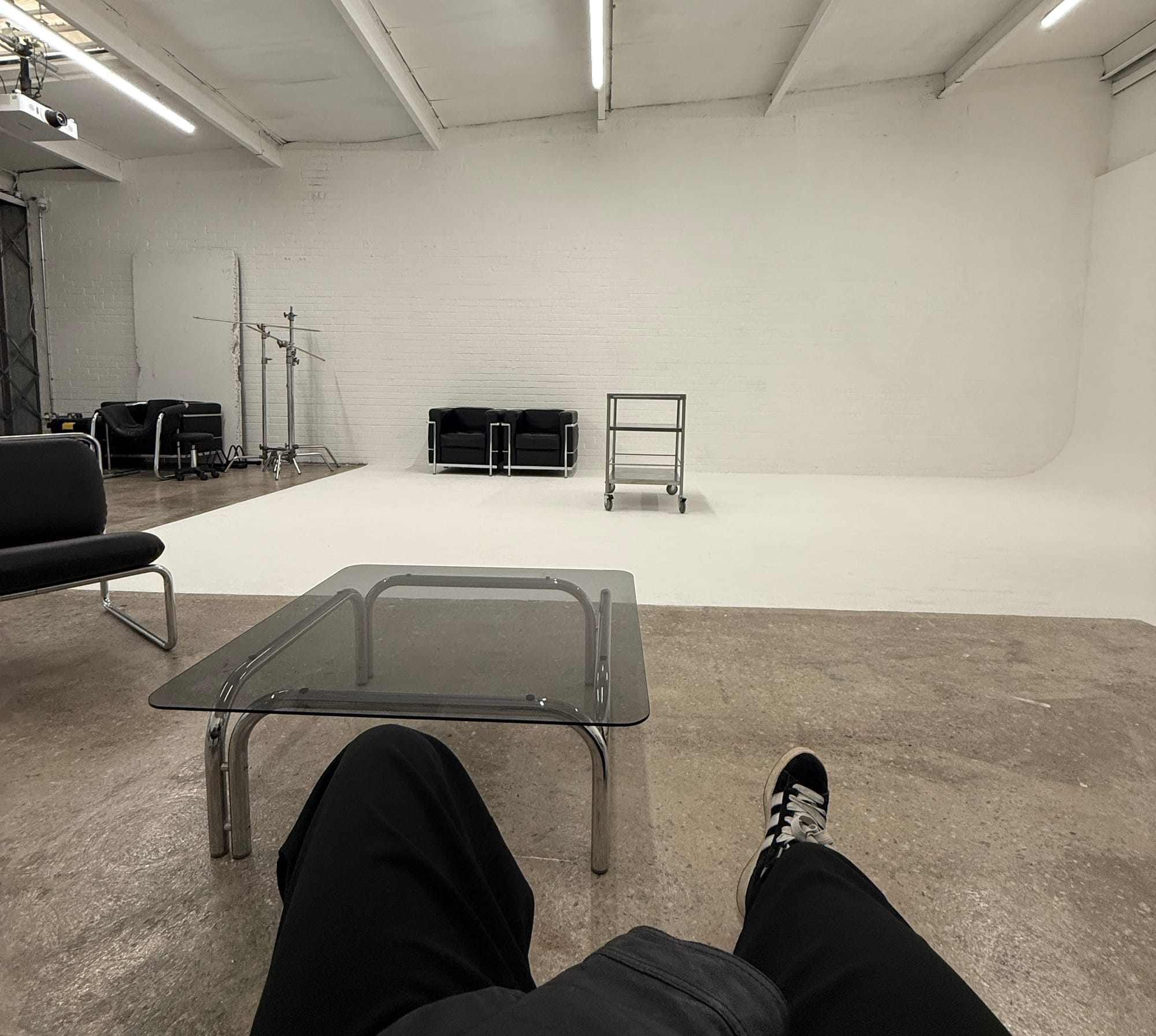 Wide shot of an empty photography studio with white walls, a cyclorama, and seating area.