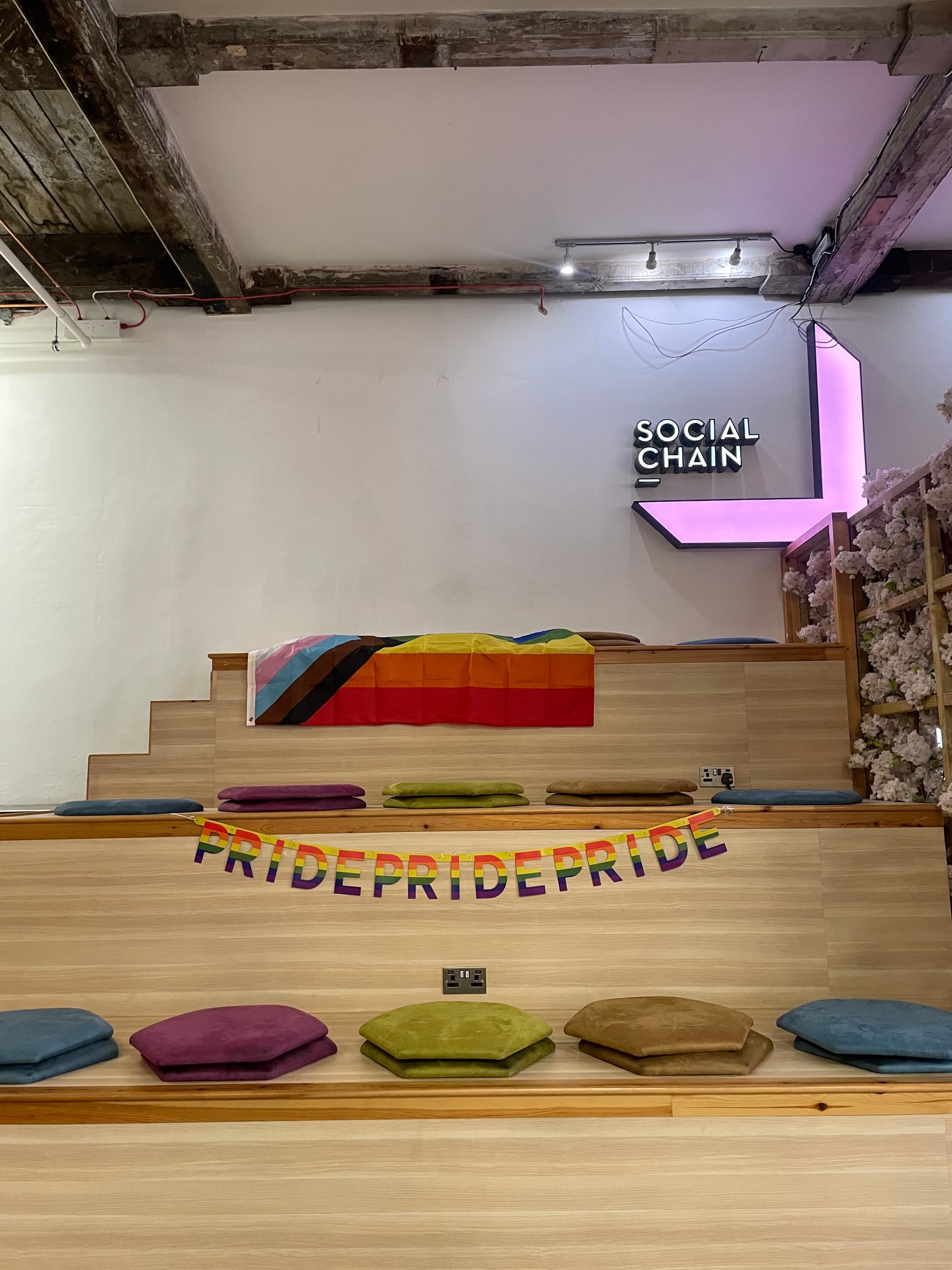 An office space stairs, covered in cushions and "pride" bunting.