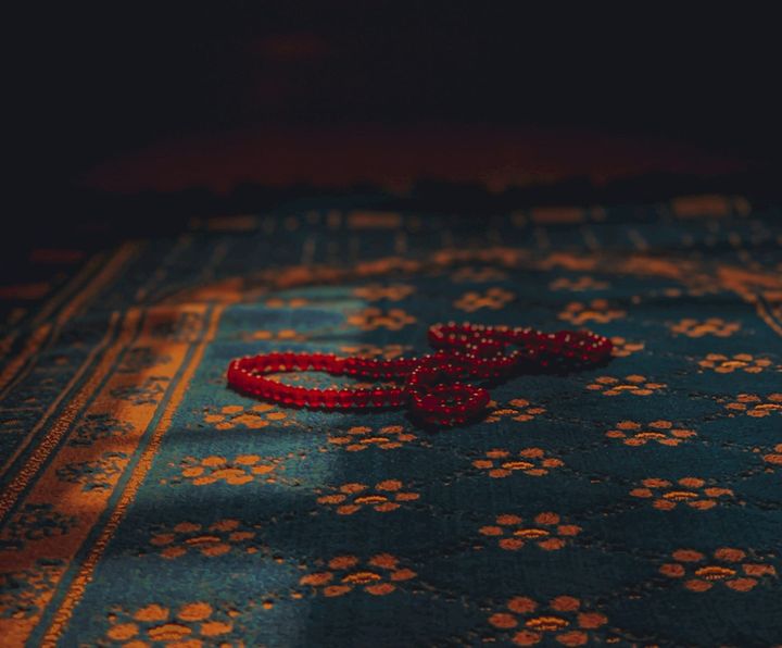 Blue and gold prayer mat with red tasbeeh on top