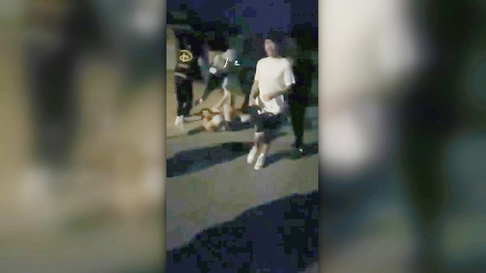 Group of attackers surrounds a boy lying on the street