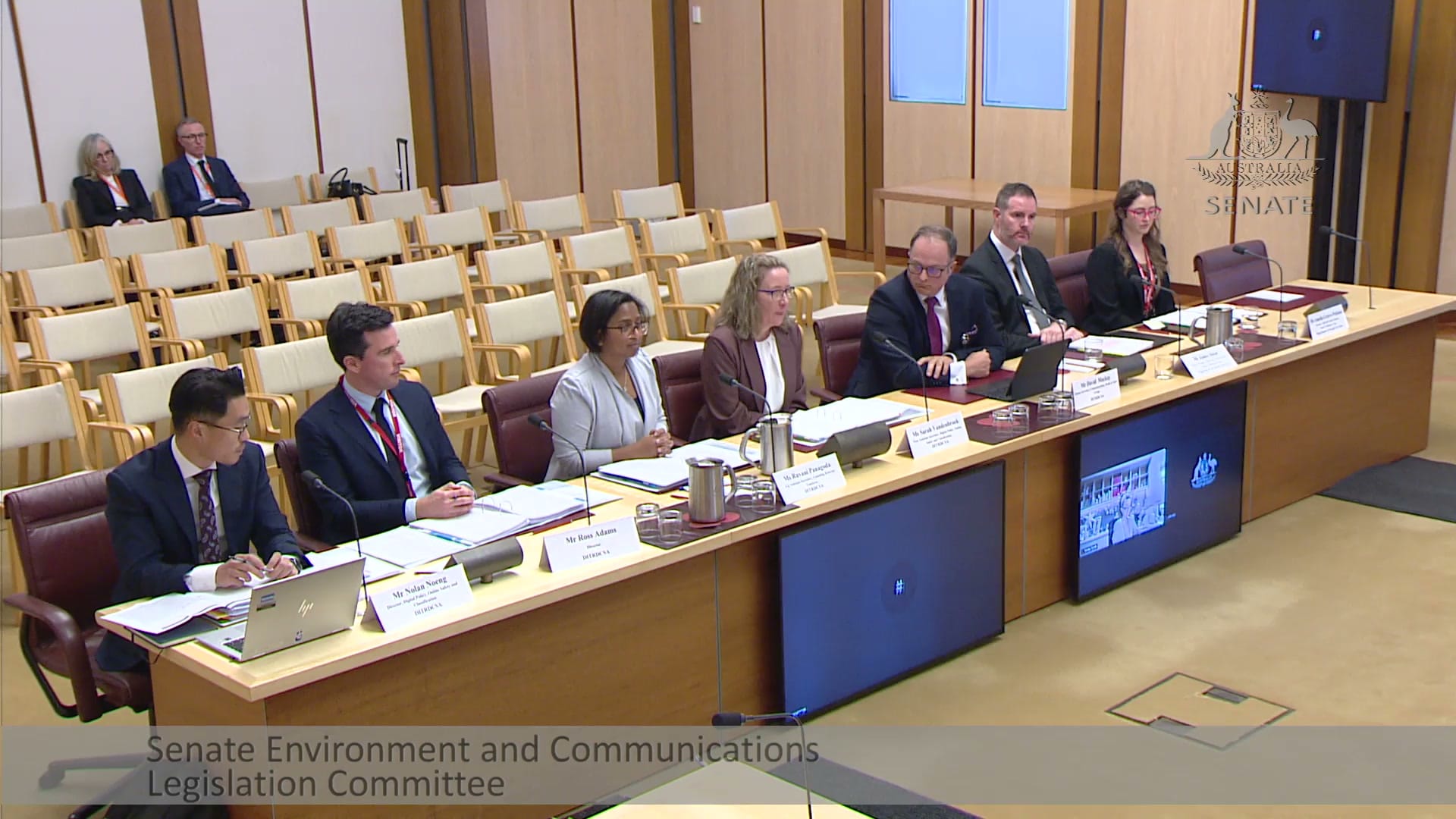 Departmental officials seated at the Senate committee table on 4 August
