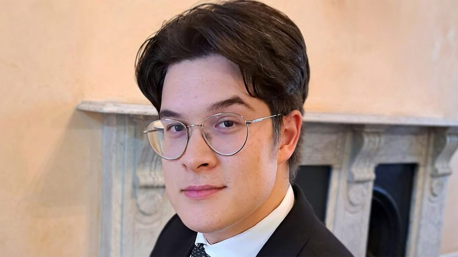 Aaron Sanford wearing round glasses and a dark suit