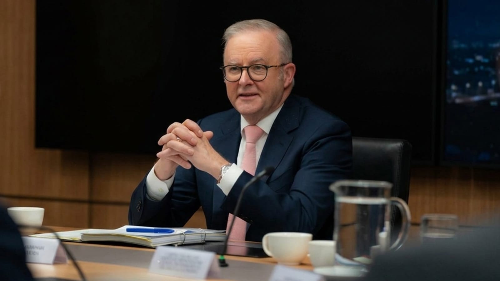 Anthony Albanese seated at a boardroom table with papers and a microphone