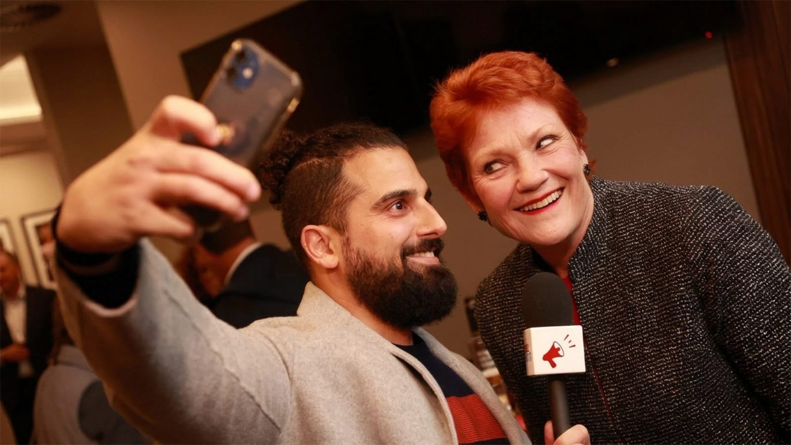 Rebel News reporter takes a selfie with Pauline Hanson holding a microphone.