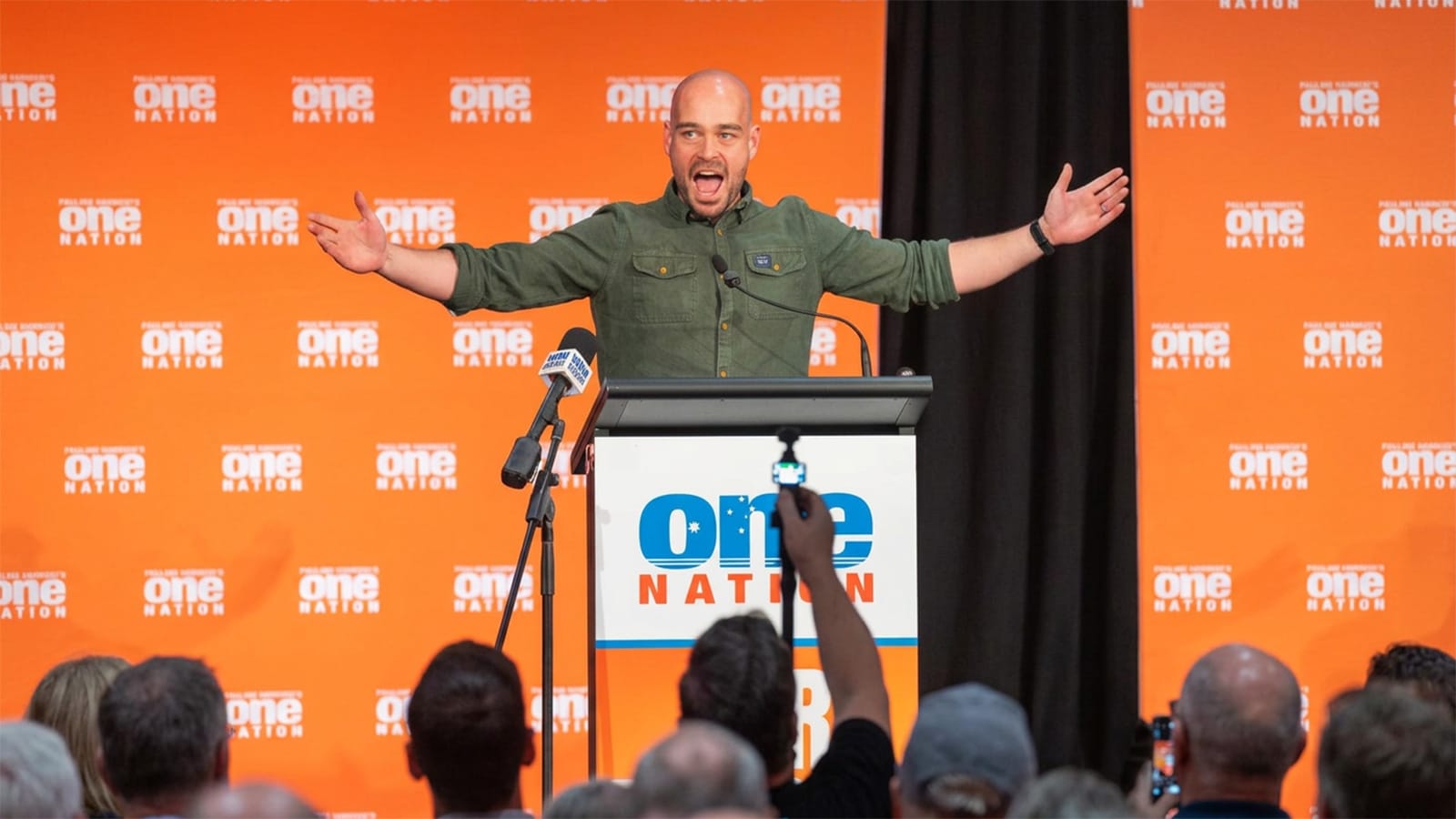 Mark Nicholson with arms spread wide at a One Nation lectern