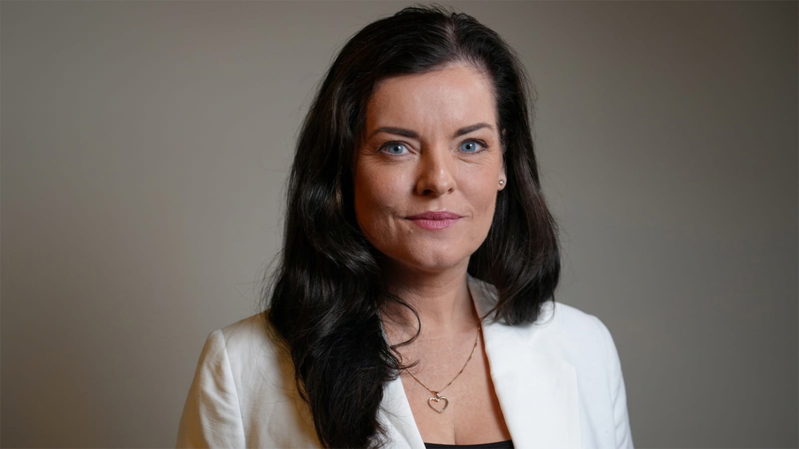 Rikkie-Lee Tyrrell in a white blazer against a dark background