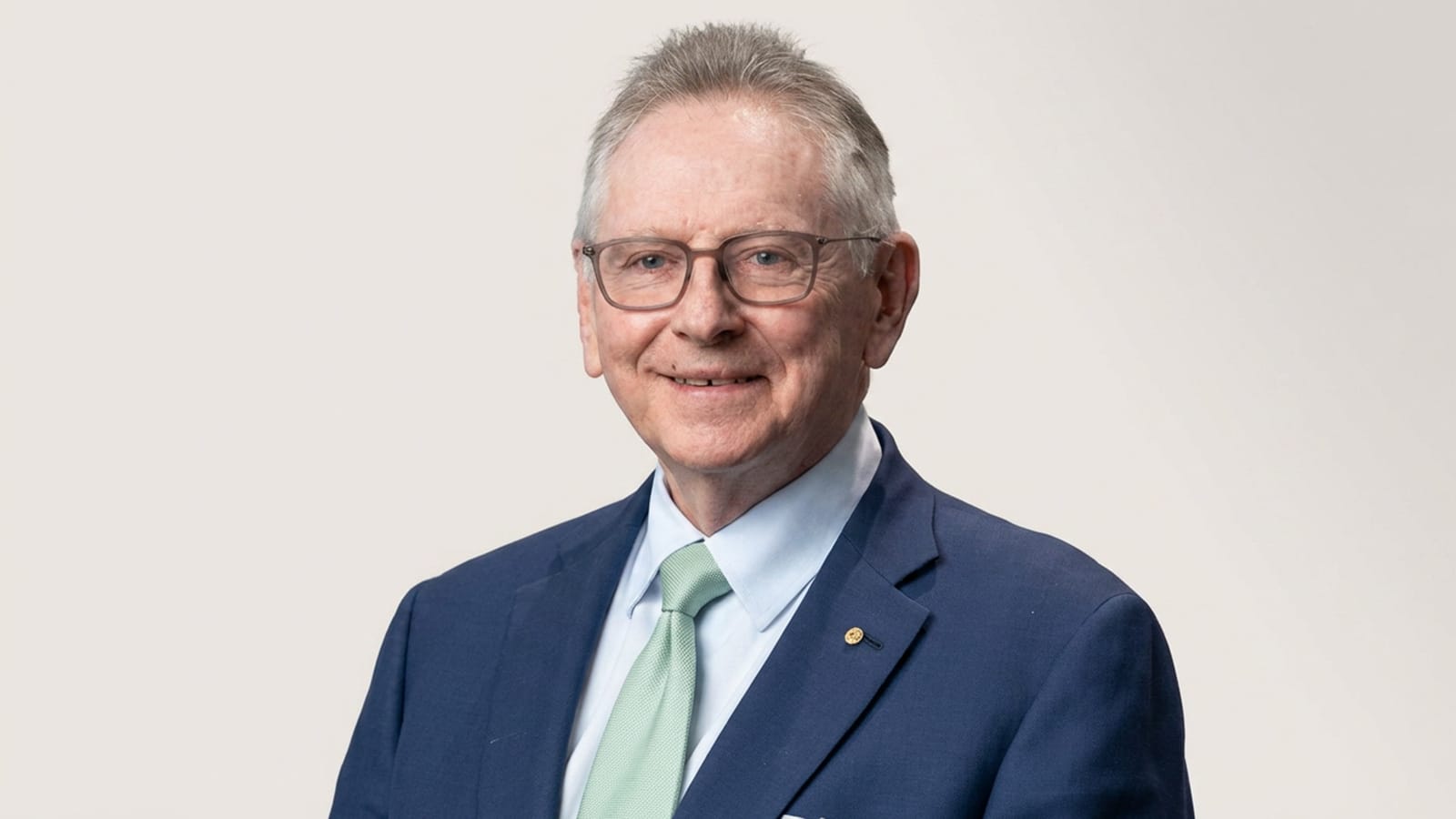 Steven Skala in a corporate portrait wearing a navy suit and glasses.