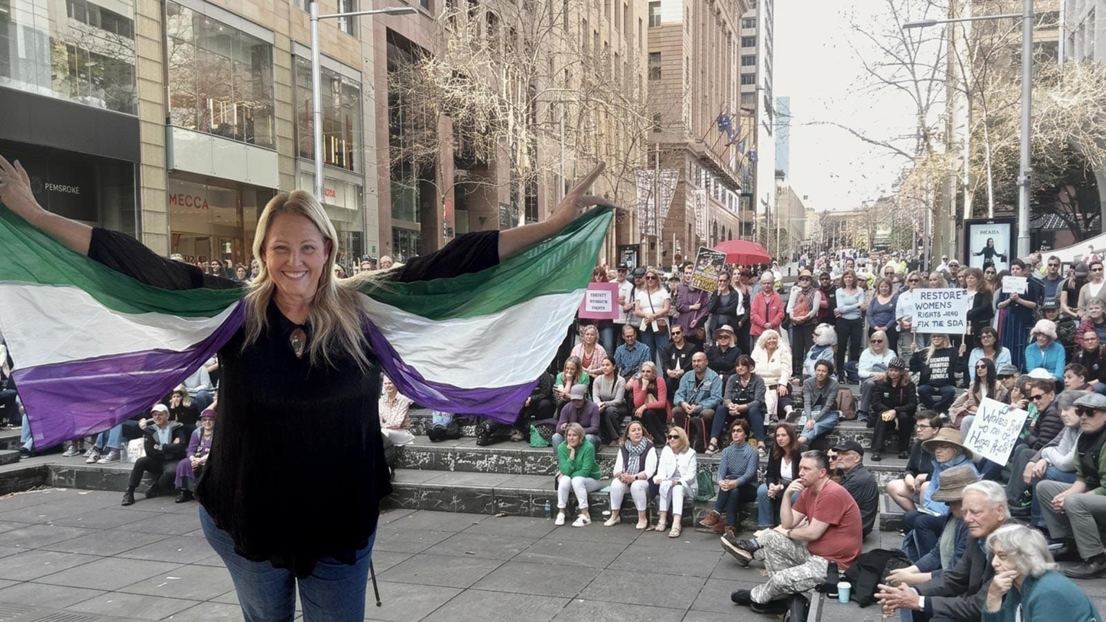 Kirralie Smith holds a suffragette flag before the Martin Place rally crowd.