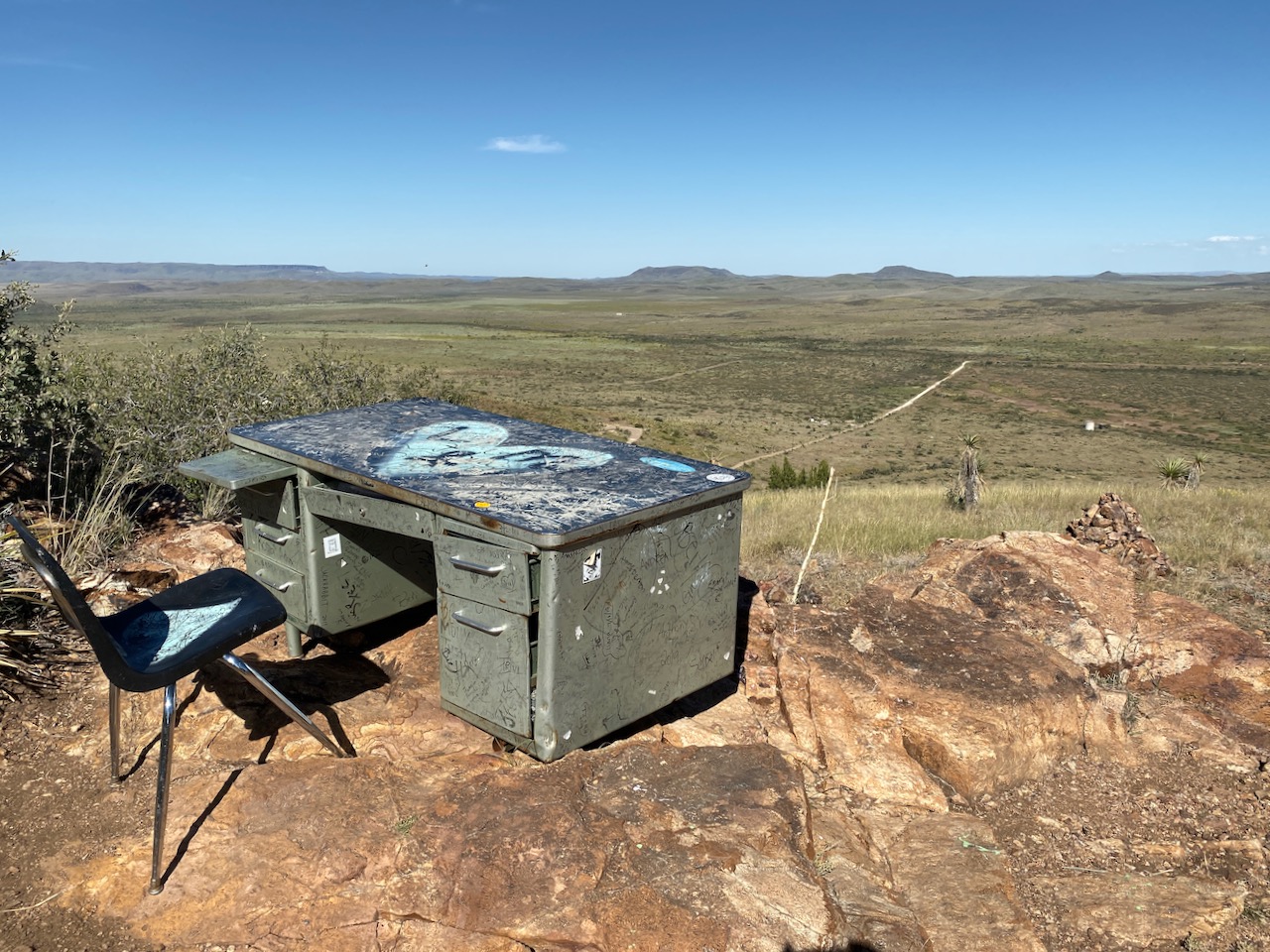 A desk sitting atop a short mountain overlooking an empty landscape.