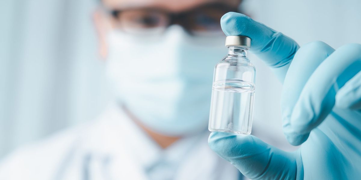 Gloved hand holding vaccine vial