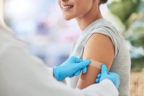 Woman's arm being bandaged after vaccine